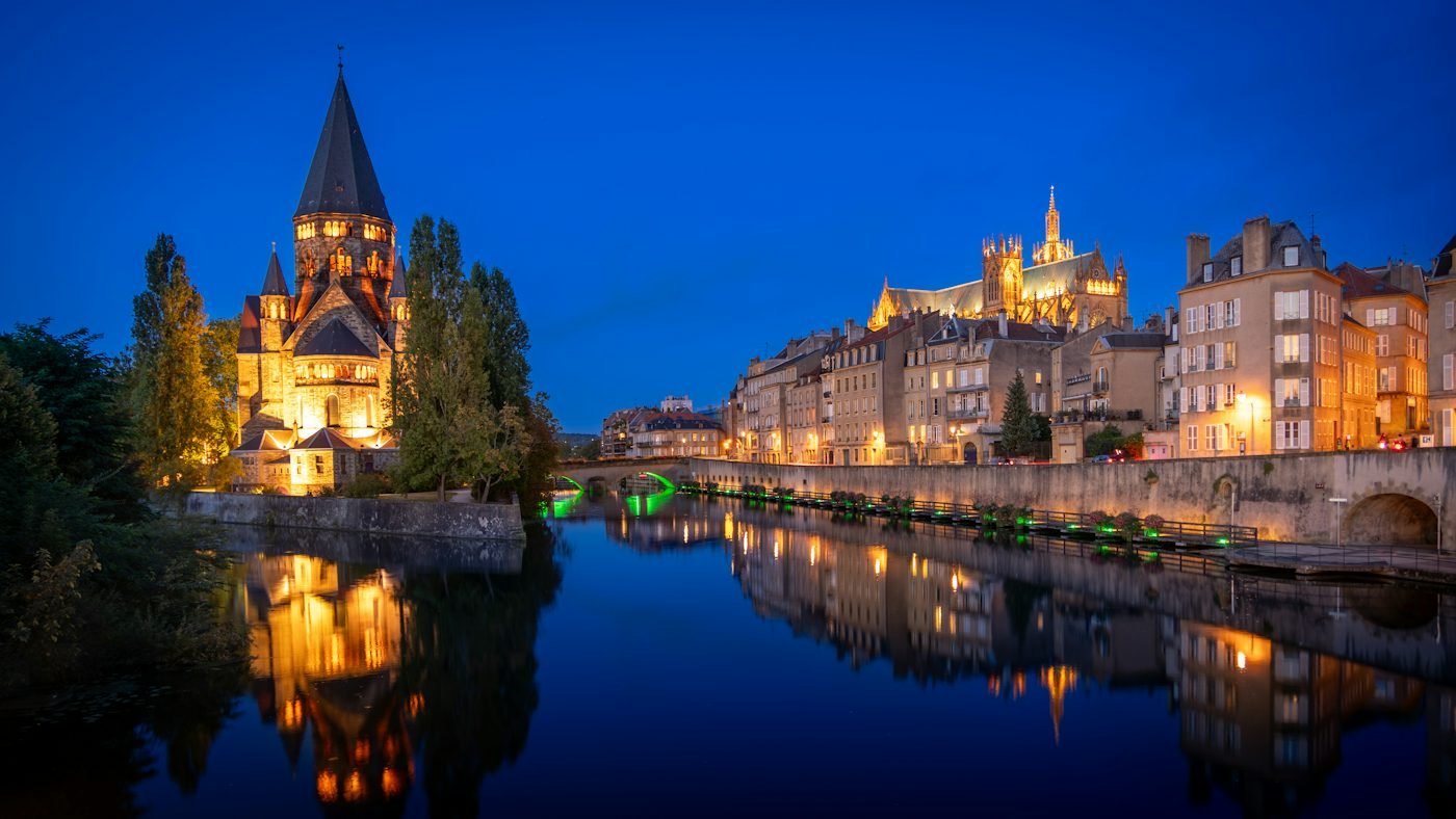 Metz de nuit : le Temple Neuf et la cathédrale Saint-Étienne au bord de la Moselle